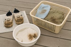 泥汚れがついた子ども服と靴を、洗濯前にベランダで準備している様子